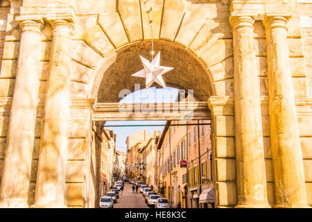 La Stella di Natale è appesa alla porta 'porta Valbona' nella città medievale murata di Urbino, Regione Marche, Italia. Via 'Mazzini' alle spalle. Foto Stock