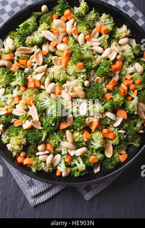 Broccoli con arachidi e carote close-up su una piastra nera. Verticale in alto consente di visualizzare Foto Stock