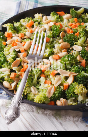 Integratore con insalata di broccoli, carote e noccioline close-up su una piastra verticale. Foto Stock