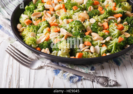 Insalata estiva con broccoli, carote e noccioline close-up su una piastra orizzontale. Foto Stock