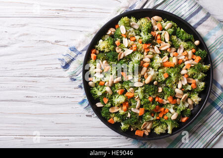 Insalata estiva con broccoli, carote e noccioline close-up su una piastra orizzontale di vista da sopra Foto Stock