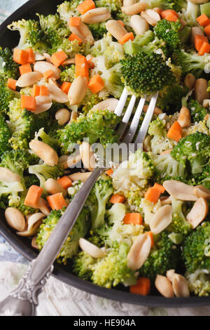 Integratore con insalata di broccoli, carote e noccioline close-up su una piastra verticale vista superiore Foto Stock