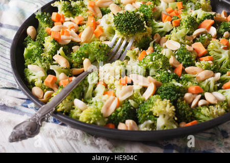 Una sana insalata con broccoli, carote e noccioline close-up su una piastra orizzontale. Foto Stock