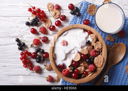 A base di cereali con latte e frutti di bosco freschi in una ciotola di legno. vista orizzontale dal di sopra Foto Stock