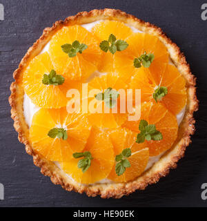 Arancione deliziosa torta con crema bianca e menta al buio su un tavolo vicino. vista da sopra Foto Stock