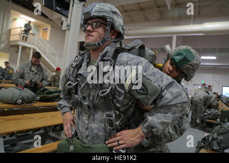 Stati Uniti Pfc dell'esercito. Donovan Davis assiste Spc. Andre Selivanov, anteriore, don il suo paracadute mentre si prepara per una notte vai alla mobilità articolare complessa, Base comune Elmendorf-Richardson, Alaska, Marzo 31, 2016. Davis, Selivanov e i soldati della quarta brigata Combat Team (airborne), XXV divisione di fanteria, appartengono al solo American airborne brigade nel Pacifico e sono addestrati per eseguire le manovre di volo in condizioni di freddo intenso/ambienti ad altitudini elevate a sostegno del combattimento, partenariato e disaster relief operations. Alejandro Pena) Foto Stock