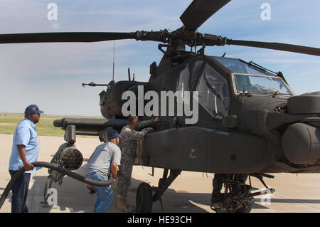 Tre Stati Uniti Esercito, AH 64 Delta elicotteri Apache di terreni a Sheppard Air Force Base in Texas, per il rifornimento di carburante in rotta verso Fort Carson, Colo., il 14 agosto 2014. Stati Uniti Army Chief Warrant Officer 2 Anthony Bailey apre la porta del carburante per rifornire il suo elicottero con l'assistenza di James Wallace e Sammy Ellis, appaltatori di base da effettuare il rifornimento di gestione. Danny Webb Foto Stock