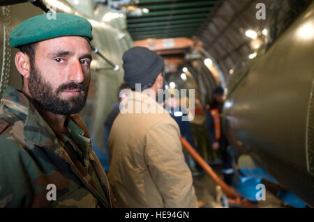 Un esercito nazionale afghano air corps airman attende per aiutare a scarico parti per tre ristrutturato di recente Mi-17 di elicotteri che sono arrivati qui su un AH-124 piano di trasporto. Il ANAAC viene supervisionato su tutti gli aspetti delle operazioni di volo da aviatore dal 438th Air Expeditionary ala. Foto Stock