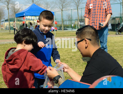 Jadyn e Ethan Wu get candy dopo aver vinto una borsa toss gioco durante la Croce Rossa il carnevale, 19 marzo 2016, presso la base aerea di Aviano, Italia. L'Aviano La Croce Rossa Americana capitolo ha ospitato l'evento nel riconoscimento della Croce Rossa Americana al mese. Senior Airman Austin Harvill Foto Stock