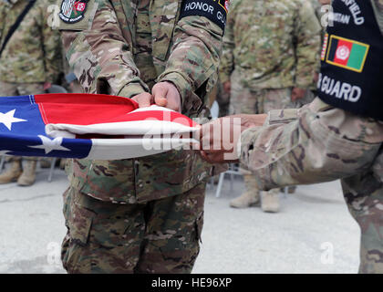 Stati Uniti Air Force aviatori assegnati alla base la guardia d'onore team piegare la bandiera durante un ritiro cerimonia in onore di operatori speciali che sono stati uccisi 4 Marzo 2002 durante l'Operazione Anaconda: U.S. Air Force Senior Airman Jason Cunningham, U.S. Esercito Cpl. Matteo Commons, U.S. Army Spc. Marc Anderson, U.S. Army Sgt. Phillip Svitak, U.S. Army Sgt. Bradley Crose, U.S. Navy Petty Officer 1. Classe Neil Roberts e U.S. Air Force Tech. Sgt. John Chapman, Marzo 4, 2015 in Bagram Air Field, Afghanistan. Servizio membri provenienti da tutti i rami condotta 24 ore di veglia e di eseguire un ritiro cerimonia per onorare il XIII un Foto Stock