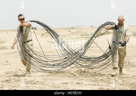 Airman 1. Classe Kenneth William, sinistra e Senior Airman Matthew Parker, 407 comunicazioni Expeditionary Squadron (ECS), eseguire una lunghezza della fibra ad una nuova posizione in modo che possano continuare ad alimentare in un fresco fosso intagliato durante un'installazione, 31 Luglio su Ali Air Base, Iraq. I Cani del cavo dalla ECS prevista più di 1200 piedi di fibre e cavi in rame per consentire una nuova unità per spostare in un edificio rinnovato su base. Foto Stock