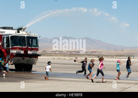 Avieri dal 99th ingegnere civile squadrone dei Vigili del fuoco ha aiutato i bambini dal Candlelighters cancro infantile Fondazione del Nevada raffreddarsi spruzzando acqua in aria per loro di giocare nel Giugno 8, 2013, presso la Base Aerea Militare di Nellis Nev. La 99th CES dei Vigili del Fuoco ha fornito un camion dei pompieri per un tour di base ospitato dal 64th Aggressor Squadron per la CCCFN. ( Staff Sgt. Gregorio Brook) Foto Stock