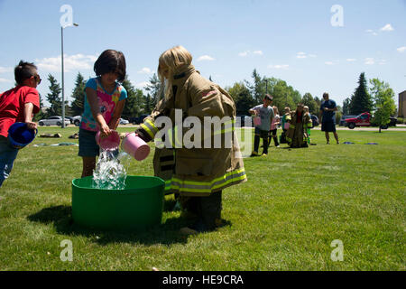 Bambini da Fairchild della Gioventù programma estivo versare acqua in un secchio durante un estate giovani prevenzione antincendio camp, 1 luglio 2015, a Fairchild Air Force Base, nello Stato di Washington I figli di re-emanate le tecniche dei vigili del fuoco usata prima di avere la manichetta antincendio, con un secchio e un secchio di acqua. Foto Stock