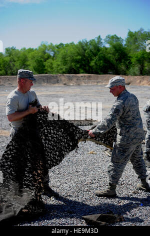 Avieri dal 376 Expeditionary ingegnere civile Squadron smilitarizzare camouflage netting in una azienda di rifiuti cantiere qui il 9 maggio 2014, in preparazione per il centro di transito a Manas, il Kirghizistan, la chiusura di questa estate. Master Sgt. Jerry Ray, un customer service operations manager da Pensacola, Fla., distribuito da Travis Air Force Base e Staff Sgt. Michael Jose Reyes, un elettricista da Leesville, La., chi è distribuito qui da Little Rock AFB, arca. lo strappo del netting in piccoli pezzi inutilizzabili che sono meno di 12 pollici quadrati. Il Centro di Transito a Manas è stato il premier un trasporto Foto Stock