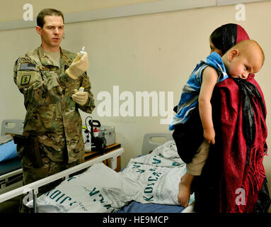 Il Mag. Marcus Neuffer, 455th Expeditionary gruppo medico oculista, spiega le direzioni di applicazione per la medicina a dodici mesi del bambino della madre in ospedale coreano Bagram in campo aereo, Afghanistan, 7 luglio. Il ragazzo è stato diagnosticato con cataratta fra le altre condizioni. Neuffer è attualmente il solo medico su Bagram che si è qualificato per operare sugli occhi. Se un paziente entra in uno degli ospedali umanitari, il coreano o ospedale egiziano, e necessità di una chirurgia oculare, essi vengono portati all'ospedale americano. Secondo Nueffer, un bambino's eye vista smette di sviluppare a circa otto Foto Stock