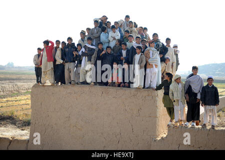 Gli abitanti afghani osservano l'arrivo di un elicottero in un avamposto del corpo dei Marines nel distretto di Pusht Rod, Afghanistan. Gli anziani del villaggio partecipano a una riunione della Shura all'interno di una tenda militare per discutere il governo locale e l'impegno della comunità. Foto Stock