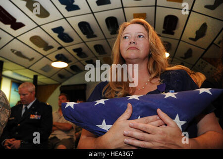 Un capo alla moglie di Brantley Cornelia, tiene la bandiera ha presentato a suo marito Chief Master Sgt. John Brantley durante la sua cerimonia di pensionamento, 18 maggio 2012, a Barksdale Air Force Base, La. come un 24-anno coniuge militare, sopportò molte separazioni e sollevato quattro figli come il suo amato servita intorno al mondo. Ora, due dei suoi figli sono anche servire nella Air Force. Foto Stock