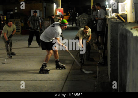 Stati Uniti Esercito 1Lt. John Leever, Delta società di manutenzione del veicolo, 1° Brigata Team di combattimento, XXII Battaglione, 4a divisione di fanteria, raggiunge per il puck durante il notturno hockey gioco in avanti una base operativa Falcon, Iraq, nel febbraio 9, 2009. Foto Stock