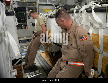 Master Sgt. Stephen Brown (destra) e Senior Airman Paolo Maginnis, 816th Airlift Expeditionary Squadron loadmasters, spingere due Contenitore sistema di consegna pacchi contenenti acqua fresca da bere in posizione su una C-17 Globemaster III in preparazione per un aiuto umanitario di airdrop al di sopra della zona di Amirli, Iraq, il 30 agosto 2014. Il velivolo è stato caricato con 40 fasci di acqua. Il personale Sgt. Shawn nichel) Foto Stock