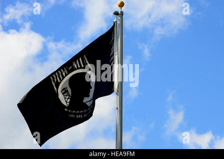 Il prigioniero di guerra/mancante in azione onde di bandiera durante la base comune Langley-Eustis, Va. POW/mia giornata di riconoscimento cerimonia alla Langley Air Force Base, Va., Sett. 18, 2015. Le immagini in bianco e nero di un gaunt silhouette, un trefolo di filo spinato e un infausto torre di avvistamento, sulla bandiera è stata progettata da Newt Heisley, un ex II Guerra Mondiale pilota. Senior Airman Kimberly Nagle Foto Stock