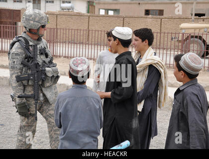 Provincia di Kandahar, Afghanistan - STATI UNITI Il personale dell'esercito Sgt. Philip Wonkka, leader di squadra per la Kandahar Provincial Reconstruction Team di sicurezza vigenti dal servente, messa. I colloqui con i ragazzi in uno spazio verde progetto a Kandahar City Giugno 13. Il progetto nel sottodistretto di nove dà locali ai bambini un luogo sicuro per giocare. Il PRT opera per migliorare la capacità di infrastruttura per migliorare la vita dei cittadini afghani. Master Chief Sgt. Richard Simonsen) Foto Stock