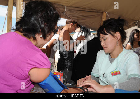 ULAANBAATAR, in Mongolia - Infermiera mongola, Alayaa Enhkman si prepara a prendere la pressione del sangue di una donna durante il pre-screening procedure al di fuori della clinica temporanea presso il Buynt Uhaa complesso in Ulaanbaatar, in Mongolia il 7 agosto durante la ricerca Khaan 2011, una combined joint-esercizio ospitato da Mongolo Forze Armate in partenariato con gli Stati Uniti Pacifico Comando forze. Ricerca Khaan è nel suo ottavo anno militare ha i partecipanti provenienti da Canada, India, Repubblica di Corea, degli Stati Uniti e della Mongolia. In aggiunta ad un medico di azione civica evento, vi è un engineering outreach event, un comando P Foto Stock