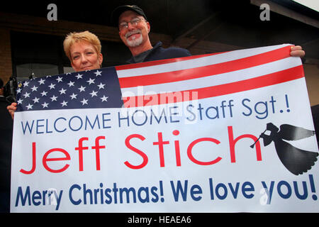 I genitori di personale Sgt. Jeff Stich orgogliosamente mostrare il loro segno accogliere i loro airman figlio di tornare a casa. L'ultimo New Jersey guardie nazionali dispiegato in Iraq restituito a base comuneGuire-Dix Mc-Lakehurst, N.J., appena in tempo per le vacanze di Natale il 20 dicembre, 2011. Il quindici aviatori dal 108th ala della forza di sicurezza Squadron distribuito su 12 Luglio a sostegno dell'operazione nuova alba. Durante la loro distribuzione, avieri condotti aria terra base missioni di difesa, che includeva il perimetro delle pattuglie, volo sicurezza linea, veicolo di ricerche e di elaborazione personale sulla base dei punti di ingresso. Foto Stock