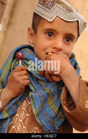 Un bambino afgano mangia caramelle nel villaggio di Shabila Kalan, provincia di Zabul, Afghanistan, nov. 30, 2009. Il personale Sgt. Christine Jones) Foto Stock