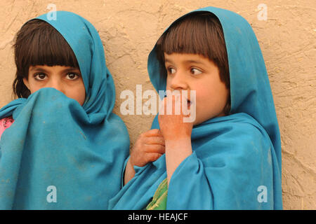 Una ragazza afgana si copre la faccia come sua sorella mangia caramelle nel villaggio di Shabila Kalan, provincia di Zabul, Afghanistan, nov. 30, 2009. Il personale Sgt. Christine Jones) Foto Stock