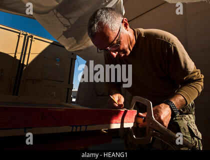 Senior Chief Petty Officer Mike Cook segna un punto di riferimento per il taglio su un pezzo di legno nel centro di transito di Manas, Kirghizistan, il 9 ottobre, 2012. Cuocere trascorre il suo tempo libero artigianali giocattolo di legno Scatole per gli amici dei bambini orfanotrofio di Sokuluk, Kirghizistan. Egli è il U.S. Forze Navali in avanti Centrale Sede portano chief petty officer di pagare il viaggio e distribuito al di fuori della stazione navale di Norfolk, Virginia, ed è un nativo di Fort Worth, Texas. Foto Stock