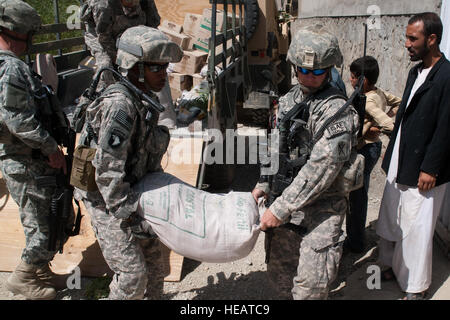 Provincia di Kapisa, Afghanistan -- STATI UNITI Army Spc. Michael Bell e Cpl. Kevin Coleman, con Team di Ricostruzione Provinciale Kapisa, scaricare 110-pound borse di cibo presso la clinica medica nel villaggio di Nijrab il 1 agosto 2010. Il cibo è parte del forte programma di alimenti che fornisce calorie-ricca nutrizione per bambini afgani durante il loro sviluppo primario anni. Il PRT ha il compito di stabilizzare la regione consentendo ai governi locali di cura, educare, impiegano e proteggere il loro popolo attraverso la costruzione di infrastrutture di base e attività di Mentor. Tech. Sgt. Joe leggi, USAF / rilasciato) Foto Stock