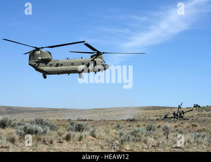 Oregon Esercito Nazionale soldati di guardia con Alfa batteria, 2° Battaglione, campo 218th reggimento di artiglieria, XLI della brigata di fanteria combattere Team, preparare per attaccare un M119A2 Obice a un CH-47, F-modello di elicottero Chinook durante un allenamento di artiglieria missione, operazione Thunderstruck, 20 giugno 2015, presso Yakima Training Center nei pressi di Yakima, Washington. Il Chinook, in prestito dalla California, è stato utilizzato per la formazione di artiglieria missione dopo i piloti dal Bravo Company, 1-168th Aviation diventare qualificati con il nuovo modello di configurazione. L'Esercito di Oregon Guardia Nazionale attualmente possiede uno F-modello e Chinook è expe Foto Stock