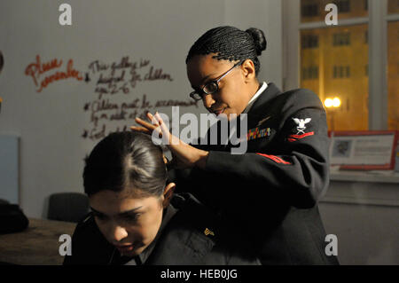 Petty Officer di seconda classe Veneszee Tiffany aiuta esercito pronto Sgt. Margaret H. Herrera, che è stato selezionato per la danza con il Presidente Barack Obama durante il Comandante in Capo della palla nel centro cittadino di Washington. Più di 5 mila uomini e donne in uniforme sono fornire assistenza militare cerimoniale di supporto al 2009 inaugurazione presidenziale, una tradizione che risale a George Washington 1789 inaugurazione. Foto Stock