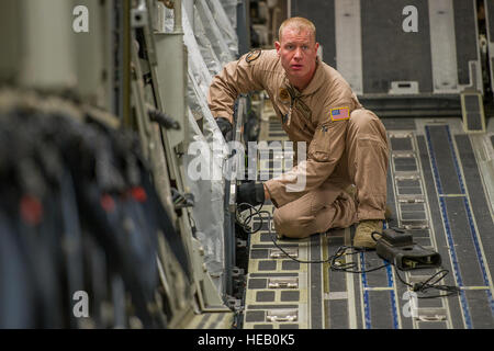 Stati Uniti Air Force Staff Sgt. Justin Volkman, 816th Airlift Expeditionary Squadron loadmaster, fissa un C-17 Globemaster III cargo area dopo un airdrop su Afghanistan, 10 gennaio. Il loadmaster calcola il carico e posizionamento del passeggero per mantenere il velivolo all'interno ammissibile del centro di gravità limiti durante tutto il volo.Volkman è distribuito dal XIV Airlift Squadron a base comune, Charleston S.C. Tech. Sgt. Dennis J. Henry Jr.) Foto Stock