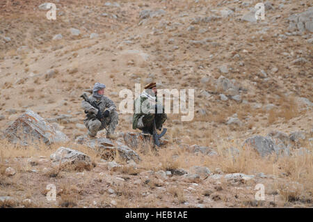 Sgt Bryan Jones, gli affari civili del Team Leader, assegnato al Team di Ricostruzione Provinciale Ghazni, e da un membro della polizia nazionale afgana tirare la sicurezza mentre i membri del PRT Ghazni eseguire un sondaggio del sito di un karza collassato nel quartiere Nawur, provincia di Ghazni, Afghanistan. Foto Stock