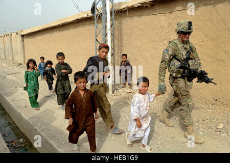 Stati Uniti Air Force 1 Lt. Michael Steuart, ingegnere civile, cammina con un gruppo di ragazzi locali durante una garanzia di qualità visita nella città Qalat, Afghanistan luglio 8. Stuart è un membro del Team di Ricostruzione Provinciale Zabul ed è distribuito da Barksdale Air Force Base, La. Foto Stock