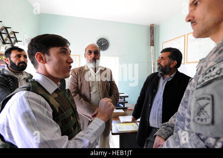 Un interprete afgano con il Farah Provincial Reconstruction Team (PRT) spiega il medico recente Shura attività al mento clinica afgane nell'asta Pusht distretto della provincia di Farah, Afghanistan, NEGLI STATI UNITI. Navy Cmdr. Harvey selvagge, il comandante del PRT team medico, Dic 29, 2009. I membri del PRT trasportati e accompagnato il Farah provinciale direttore sanitario, il dottor Abdul Jabar, (nella foto vicino a quella della Cmdr. Selvaggio) e altri Farah Hospital Medical provider per una valutazione della clinica. Questa è la prima struttura medica che ha un display del loro medical Shura nomi dei membri della famiglia e Foto Stock