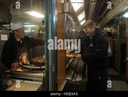 151225-N-KM956-072 BREMERTON nello Stato di Washington (Dec. n. 25, 2015) - Ernie Samaras, da Seattle, serve prime rib per comunicazioni interne elettricista 2a classe Daniel Muehlbauer, da Flagstaff, in Arizona, in cucina a poppa a bordo della USS John C. Stennis (CVN 74). Stennis' equipaggio è attualmente in porto la formazione per le future distribuzioni. La comunicazione di massa specialista di terza classe Aime Lykins / rilasciato) Foto Stock