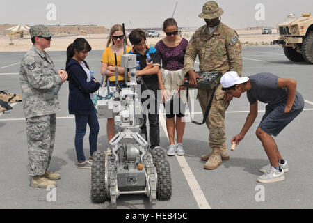 Senior Airman Joel Williams (destra) dimostra l'uso di un Remotec ANDROS F6A heavy-duty robot durante la scuola americana di Doha annuale di terzo grado 8gita Al Udeid Air Base, Qatar, Marzo 10, 2014. L'aria 379 Ala Expeditionary organizzato una gita per gli studenti mostrando la varietà delle carriere disponibili AGLI AVIATORI. Circa 150 studenti è venuto alla base per vedere come vivono gli avieri, dove lavorare e esattamente quello che fanno. Il F6A robot velocità e agilità lo rendono una scelta ideale per una vasta gamma di missioni. Il personale Sgt. Tammy Cassidy (sinistra) accompagnatori degli studenti durante la visita ed evidenzia th Foto Stock