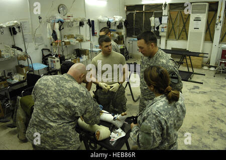 Stati Uniti Army medics dal 6° Stormo, 9 corazzate reggimento di ricognizione, 3° Brigata Team di combattimento, 1° Divisione di cavalleria fornire assistenza medica a un iracheno funzionario di polizia con pistola sparato alle ferite di entrambe le gambe in avanti base operativa della Normandia, in Iraq il 24 marzo. Il personale Sgt. Stacy L. Pearsall) Foto Stock