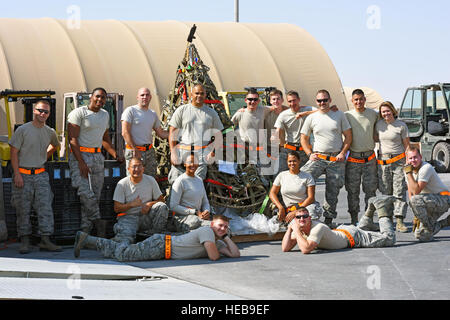 Avieri con il 8° Expeditionary Aria Mobilità Squadron pongono di fronte a un albero di Natale sono realizzati in materiali di consumo intorno a loro unità di Al Udeid Air Base, Qatar, dal 1 dicembre 2016. In uno sforzo per diffondere lo spirito natalizio intorno all'U.S. Comando centrale area di responsabilità, l'ottava EAMS prevede di distribuire questo tema natale di allegarlo al pallet multipli che saranno spediti in varie posizioni attraverso il teatro. Senior Airman Cynthia A. Innocenti) Foto Stock