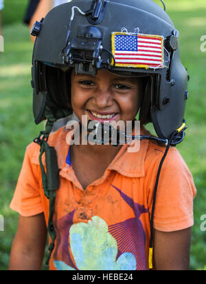 Un giovane ragazzo cerca su un aviatore casco al lago Yojoa, Honduras, 22 gennaio 2015. L'1-228esimo reggimento di aviazione in partnership con gli Stati Uniti Esercito di Operazioni Speciali personale di mettere in pratica il recupero di vivere personale. L'Overwater paranco training era tenuto a garantire i membri di Joint Task Force-Bravo sono la pianificazione e la preparazione per la crisi e di risposta di emergenza, nonché la lotta contro la criminalità organizzata transnazionale e la lotta contro il terrorismo operazioni come parte degli Stati Uniti Comando Sud la missione. La pianificazione delle situazioni di emergenza prepara il comando per vari scenari che pongono il maggior probabilità di rimettere in discussione la nostra regio Foto Stock