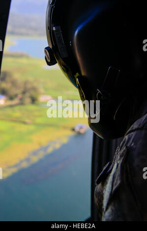 Un capo equipaggio assegnato all'1-228esimo reggimento aviazione guarda per gli Stati Uniti Esercito di Operazioni Speciali di soci in lago Yojoa, Honduras, 22 gennaio 2015. L'1-228esimo reggimento di aviazione in partnership con gli Stati Uniti Esercito di Operazioni Speciali personale di mettere in pratica il recupero di vivere personale. L'over-acqua paranco training era tenuto a garantire i membri di Joint Task Force-Bravo sono la pianificazione e la preparazione per la crisi e di risposta di emergenza, nonché la lotta contro la criminalità organizzata transnazionale e la lotta contro il terrorismo operazioni come parte degli Stati Uniti Comando Sud la missione. La pianificazione delle situazioni di emergenza prepara il comando per vari Foto Stock