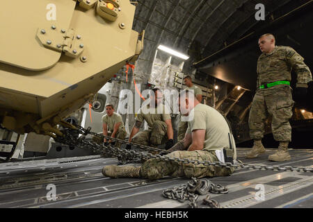 Avieri assegnato alla 455th Expeditionary porta antenna squadrone lavorano insieme per serrare i cavi che fissano una pesante mobilità estesa carrello tattico a bordo di una C-17 Globemaster III dopo off-caricare sei ambulanze afghano di Bagram Air Field, Afghanistan, luglio 20, 2014. (U.S. Air Force foto di Master Sgt. Cohen A. giovani/rilasciato) Foto Stock