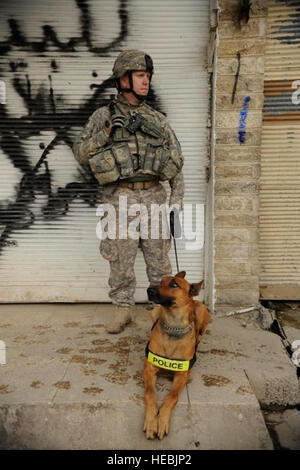 Stati Uniti Il personale dell'esercito Sgt. Michael entre, attaccato alla sede centrale e sede società, XXV divisione di fanteria, e il suo cane di polizia, Ronnie, stand-by durante una compensazione e il censimento nel quartiere Zinjali di Mosul, Iraq, 28 febbraio, 2009. (U.S. Air Force photo by Staff Sgt. JoAnn S. Makinano/rilasciato) Foto Stock