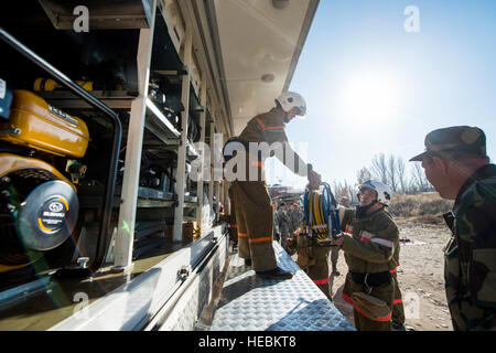 Kyrgyzstani vigili del fuoco con il Manas International Airport nload marcia dalla loro carrello di soccorso durante un veicolo extrication esercizio con U.S. Avieri con il 376 Expeditionary ingegnere civile Squadron nov. 15, 2013, al Centro di Transito di Manas, Kirghizistan. Il comando dei vigili del fuoco si sono scambiati informazioni con un altro per migliorare le loro abilità in una situazione di emergenza. (U.S. Air Force foto di Senior Airman George Goslin/rilasciato) Foto Stock