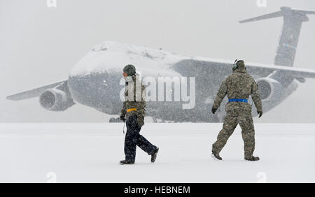 Una coperta di neve C-5M Super Galaxy si siede in background come due team membri di dover passare ogni altro sulla linea di volo a Gennaio 6, 2015, alla Dover Air Force Base, Del. base sono rimasti aperti nelle normali operazioni, nonostante il vento-azionata la neve e il freddo pungente temperature. (U.S. Air Force foto/Roland Balik) Foto Stock