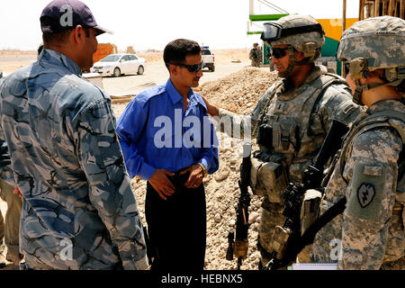 Stati Uniti Esercito 1Lt. Hugo Flores-Diaz e U.S. Esercito 1Lt. Julie Leggett (a destra) dal distacco di sicurezza, XXV truppe speciali battaglione, XXV divisione di fanteria, parlare con la polizia irachena il comando Sgt. Il Mag. Juma Jassim Mohammed e iracheno di un altro funzionario di polizia durante un micro-concessione progetto sondaggio vicino a Tikrit in Iraq, e il agosto 26. Foto Stock