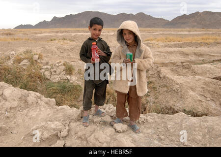 Due giovani ragazzi afghani ammirato il lavoro dei membri del Farah Provincial Reconstruction Team (PRT) come hanno scavato il loro humvee bloccato al di fuori di un fossato a 8 Dicembre, 2009, Farah Provincia, Afghanistan. I ragazzi sono stati premiati con un ice-bevanda fredda per il loro interesse. I membri del PRT è riuscito a liberare il proprio veicolo in una questione di momenti non solo mediante lo scavo di gomme, ma anche tirando il intrappolato humvee con altri due M1151's e cavi di traino. Successivamente il PRT portati con la loro missione di valutare due progetti di elettrificazione in provincia. Foto Stock