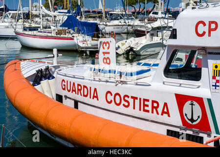 La barca a vela e barche a motore e un gommone della guardia costiera sono ancorati nel porto Foto Stock